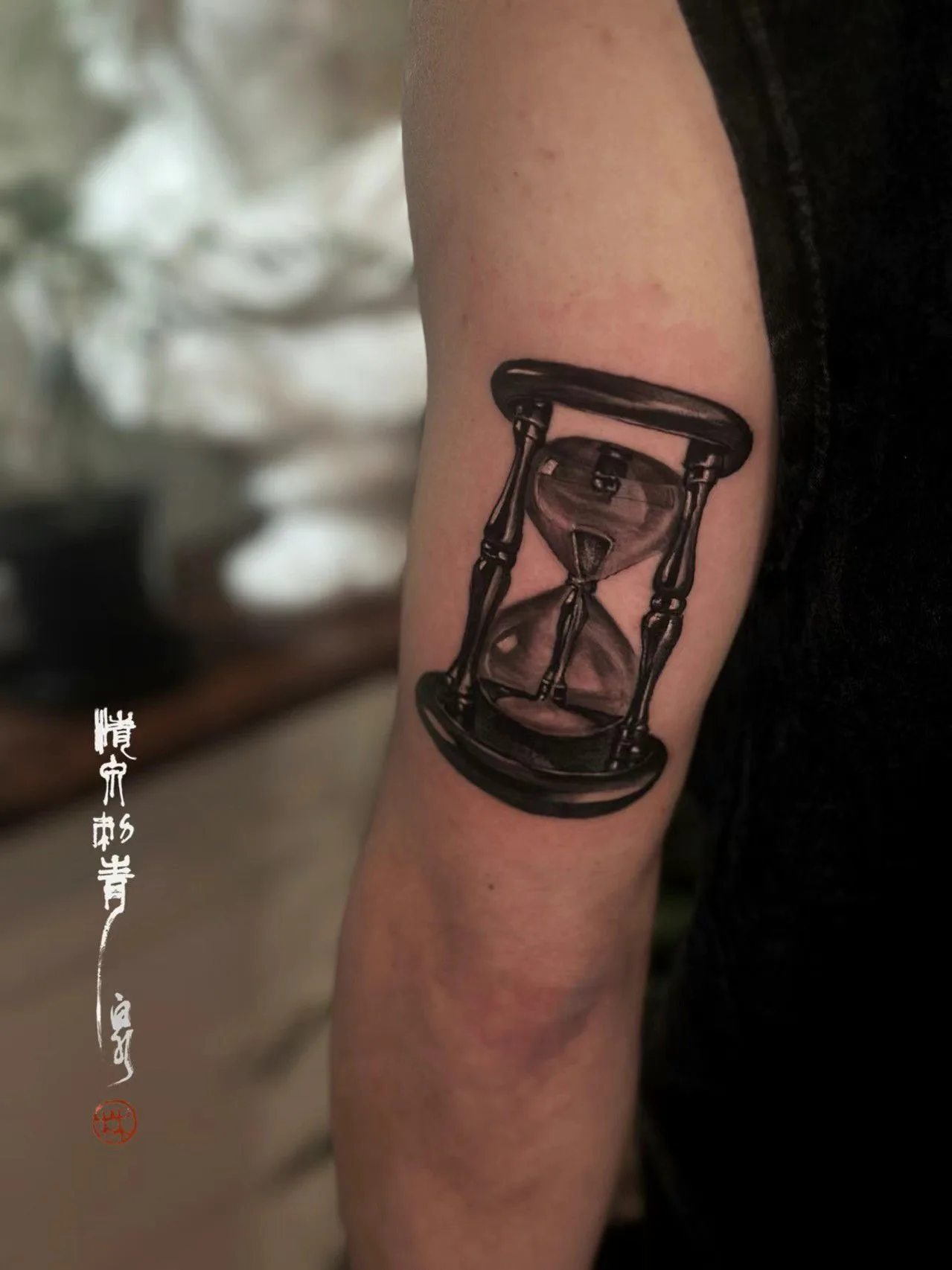 Realistic black-and-grey hourglass on a forearm