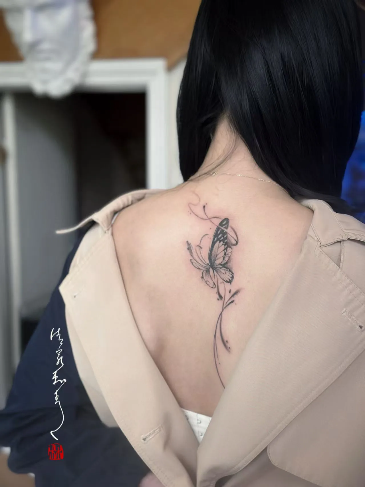 Delicate fine-line butterfly along a woman's spine